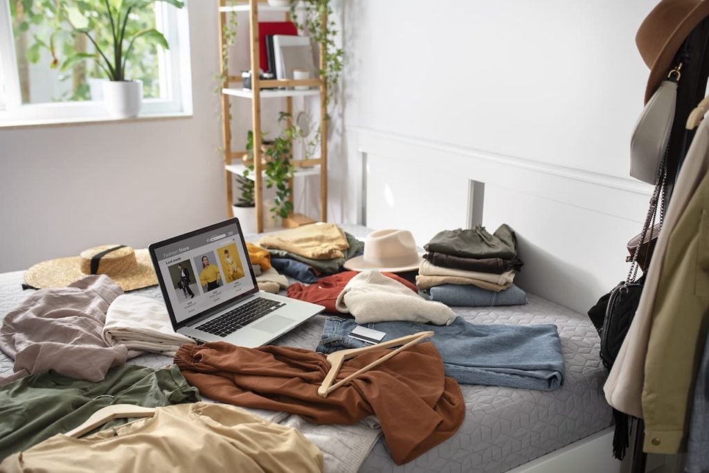 Des vêtements et un ordinateur posé sur un lit